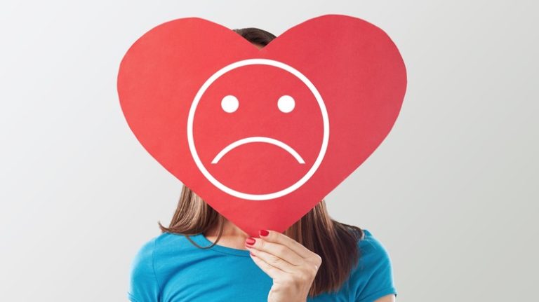 Reasons a Therapist Recommends Avoiding Self-Diagnosing Mental Health Conditions on Social Media teenager holding a sad heart over her face