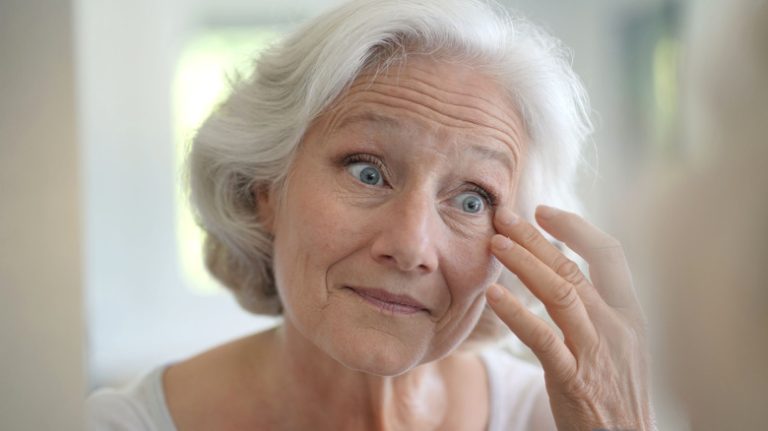 Older woman examining face in mirror